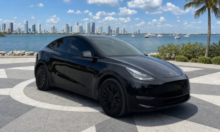 After: the same Tesla Model Y, same front three-quarter view, on a cleaner waterfront listing scene