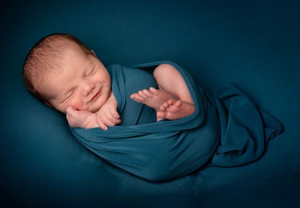 Baby photo book cover — a smiling swaddled newborn