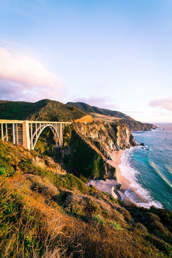 Road-trip photo book cover — a coastal bridge at golden hour